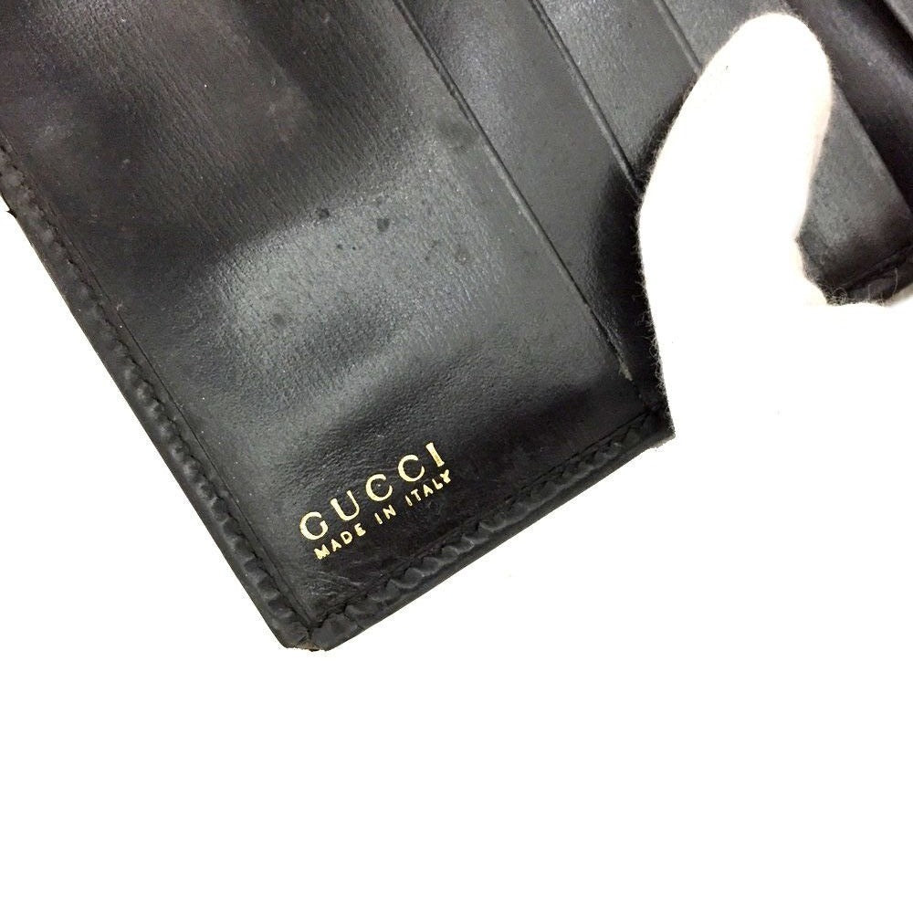Gucci, black glossy leather, bi-fold style, rectangular, wallet with multiple pockets, tons of card slots, and a gold, hinged G clasp